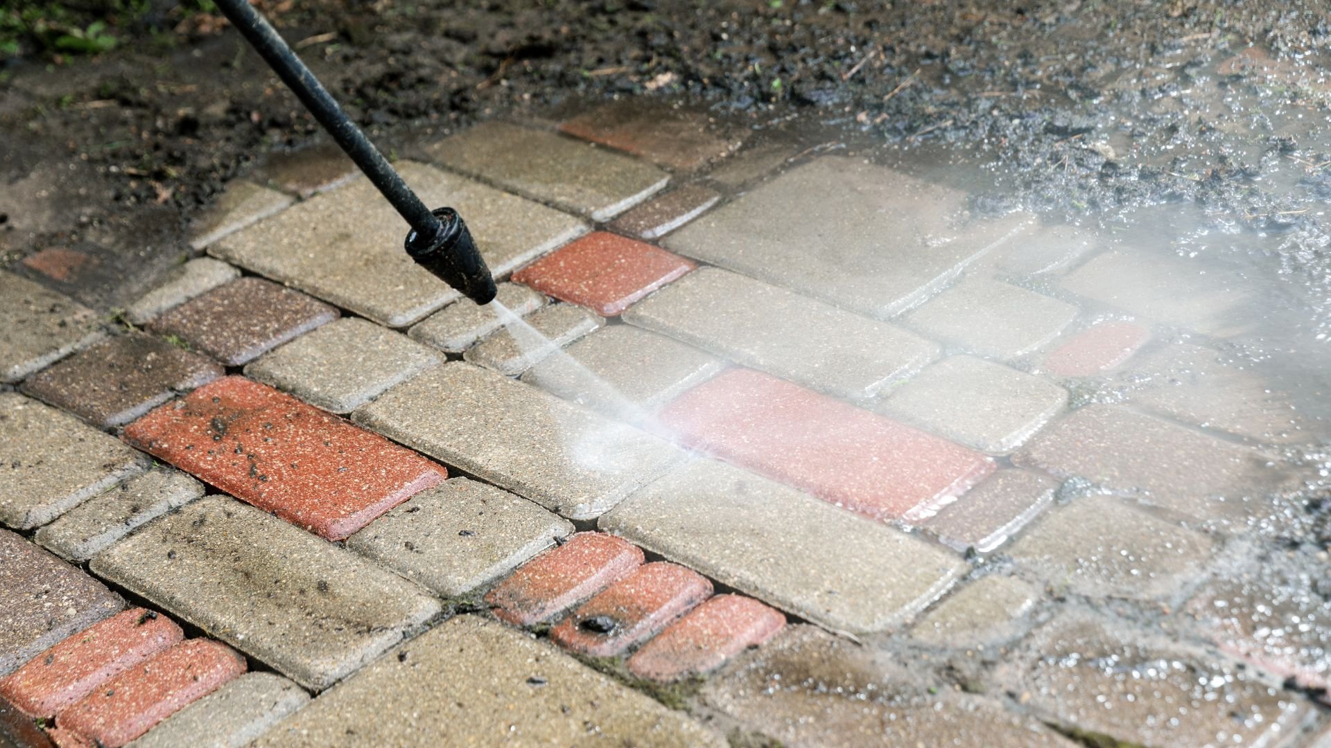 Pressure washer cleaning brick patio with water spray