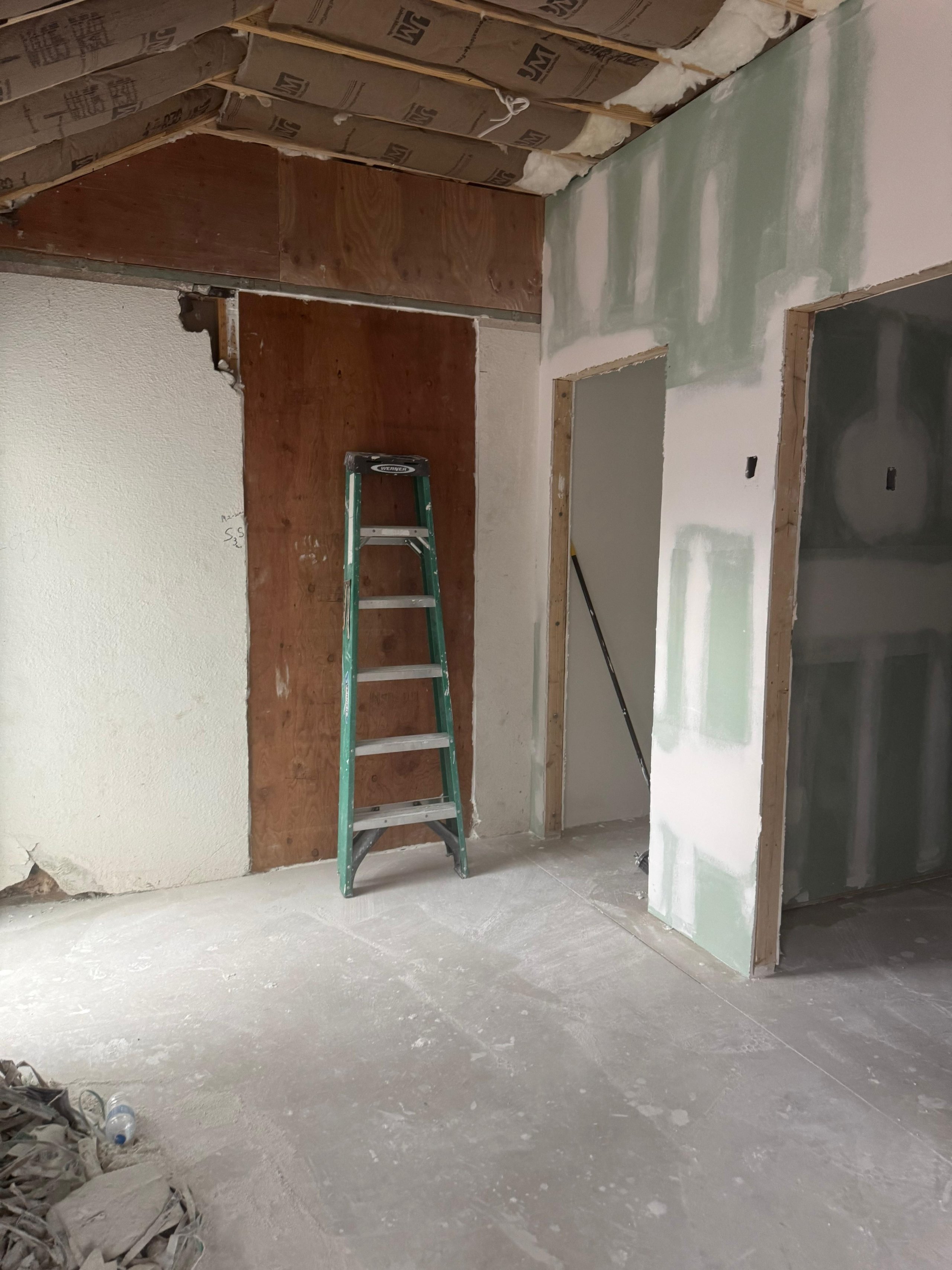 Green ladder in unfinished room with exposed walls and construction materials