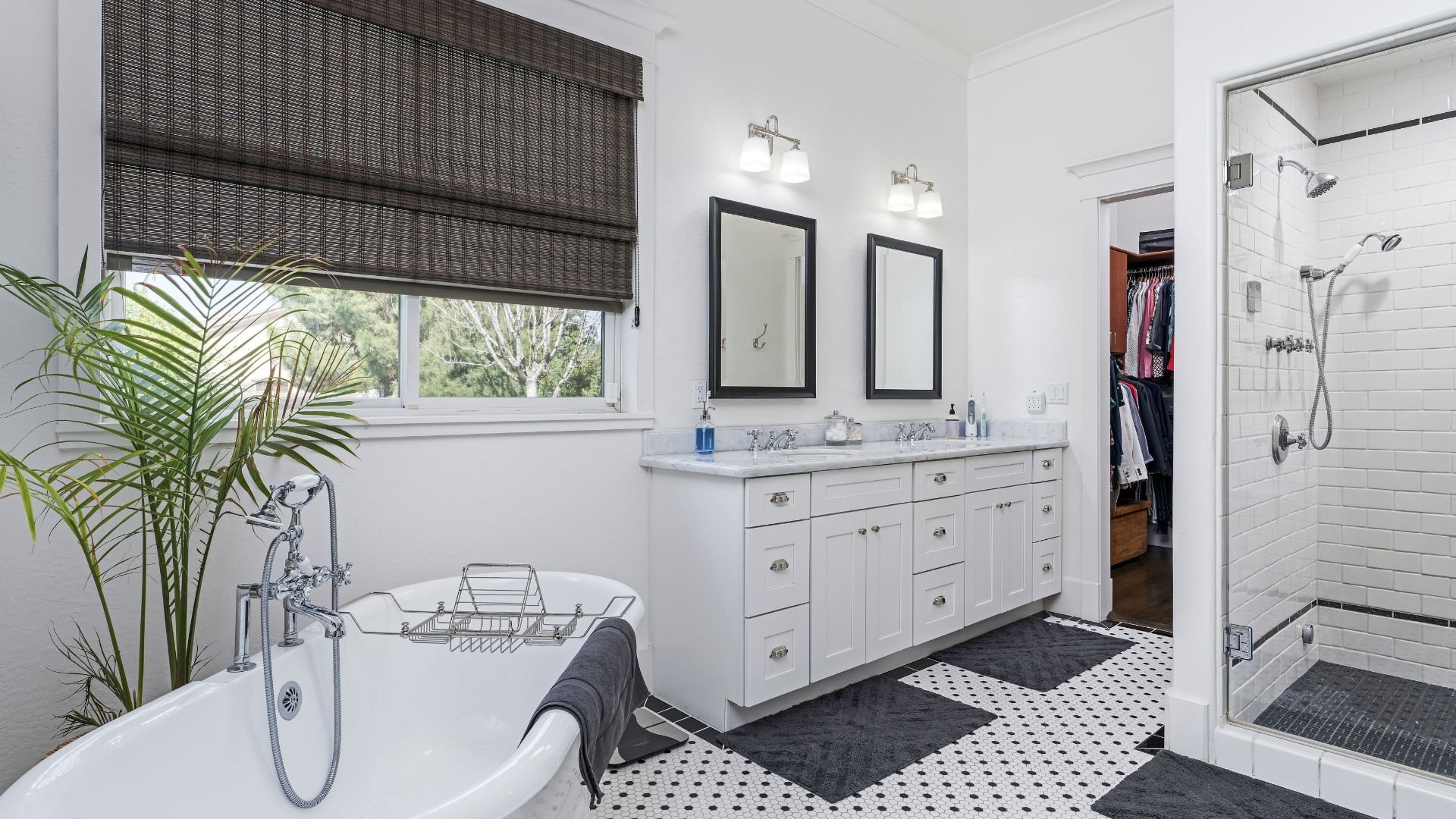 Elegant white bathroom with freestanding tub, palm plant, and walk-in shower