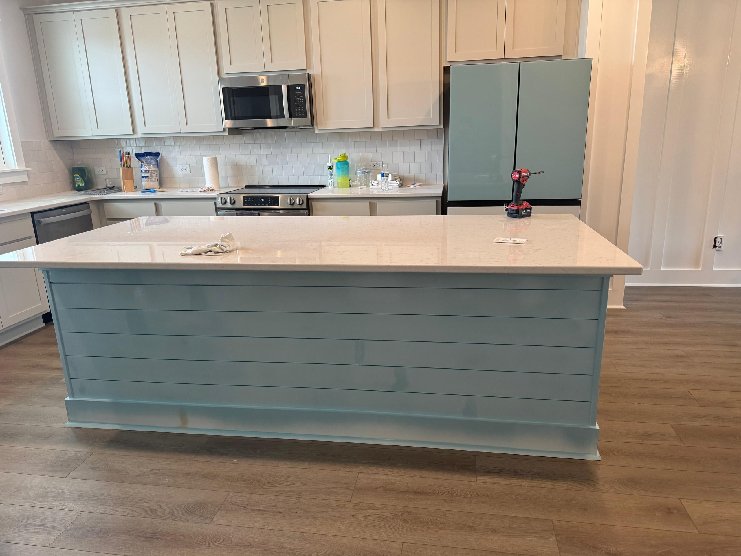Modern kitchen with blue-gray island, white cabinets, and stainless steel appliances