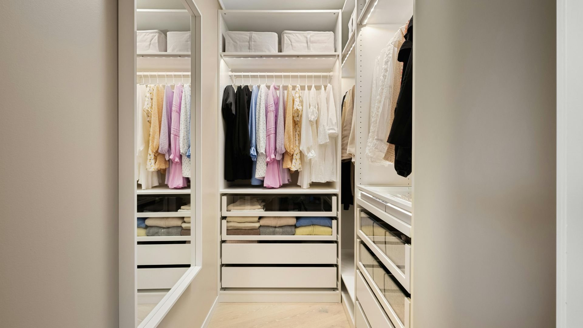 Organized walk-in closet with hanging clothes and folded items in drawers