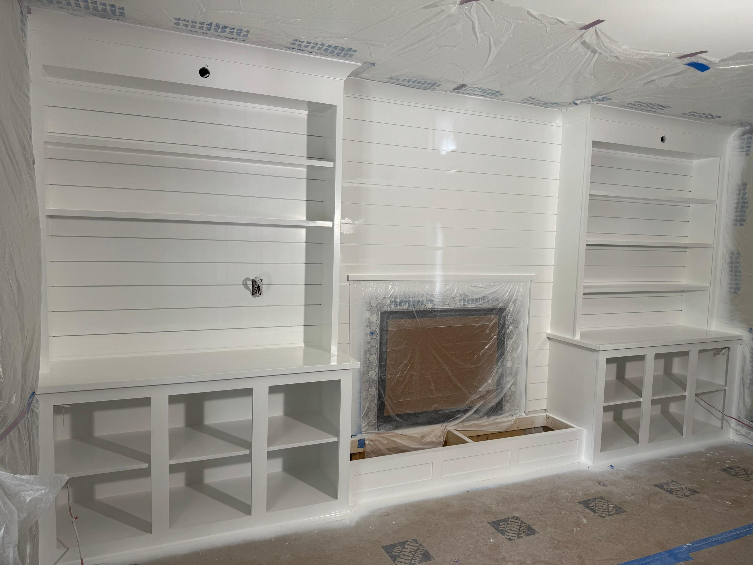 White built-in shelves and cabinets surrounding fireplace during renovation