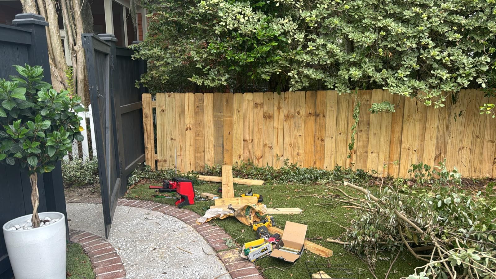 Wooden fence with construction tools and wood scraps in backyard