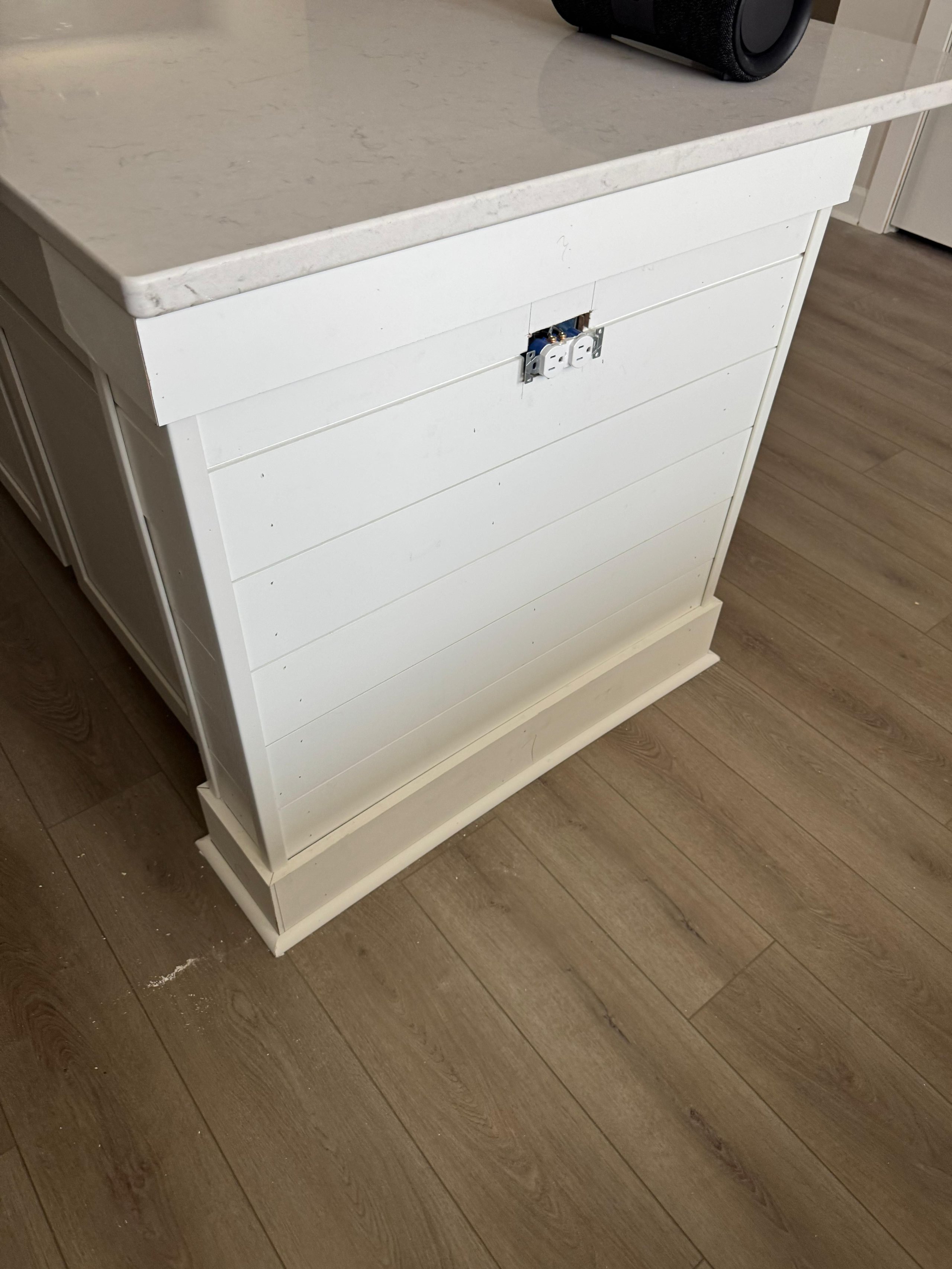 White kitchen island with electrical outlet on wooden floor